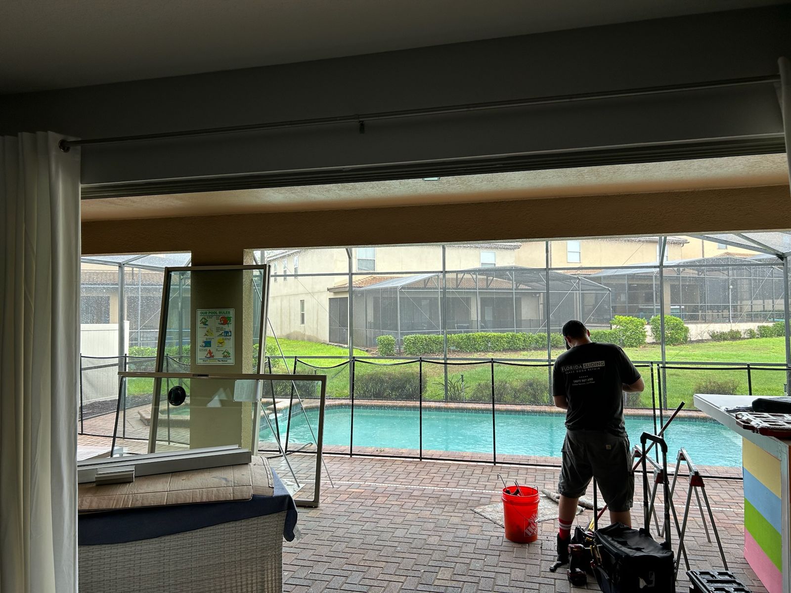 Technician repairing a sliding glass door at a screened pool enclosure — sliding glass door services in Titusville, Florida