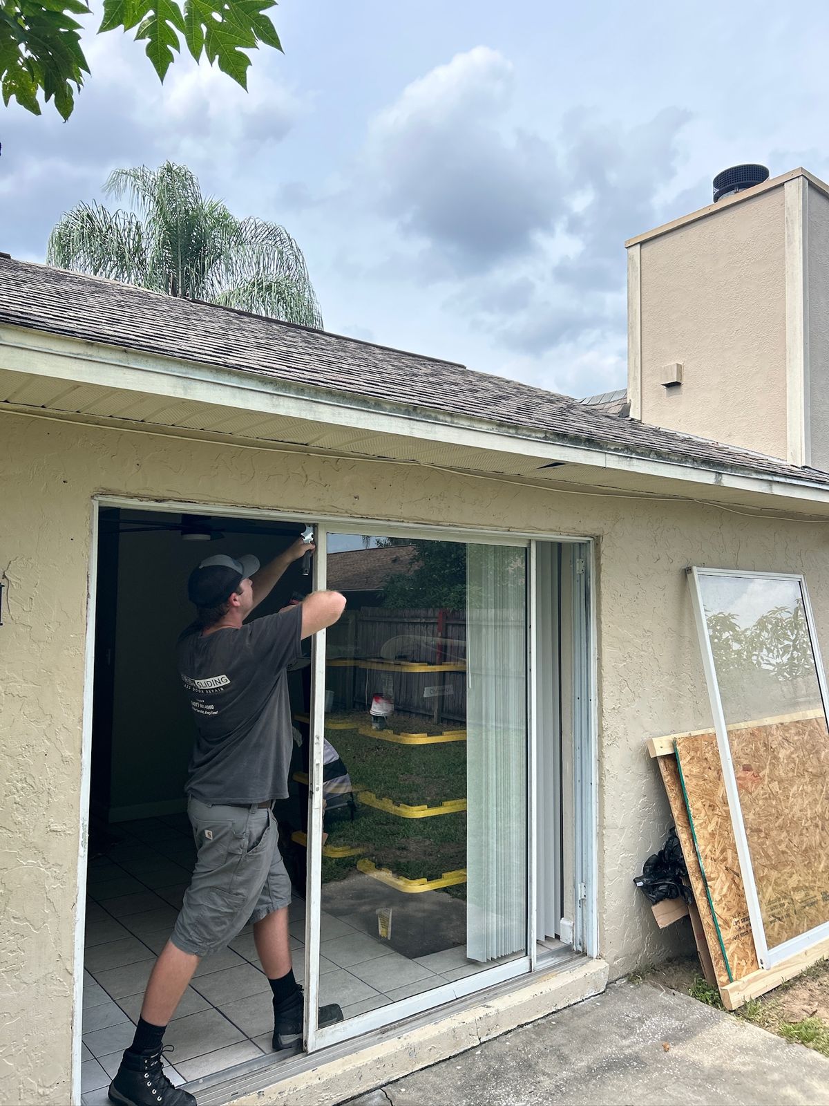 Technician carrying a replacement sliding door panel to a home — sliding glass door services in Davenport, Florida