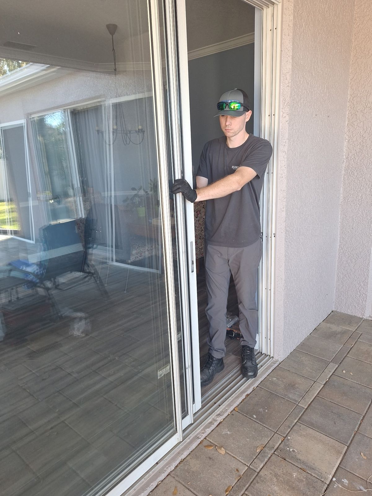Technician inspecting a sliding glass door on a back patio — sliding glass door services in Sanford, Florida